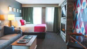 Une chambre d’hôtel avec un lit, un canapé, une table basse, une cheminée et un mur aux couleurs vives.