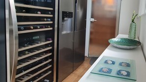 Moderni keittiö, jossa on viinijääkaappi, jääkaappi ja koristeellinen kulho työtasolla.
