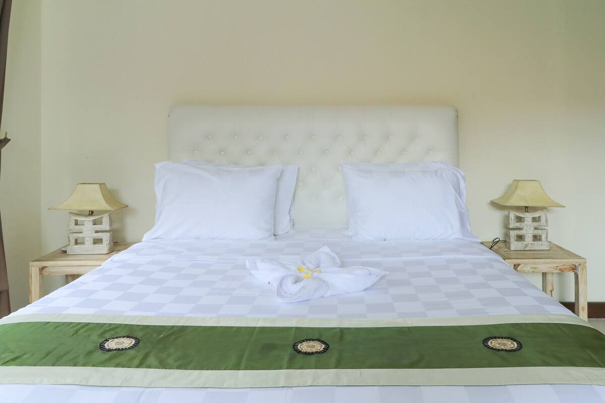 A neatly made bed with a checkered bedspread, two pillows, and a decorative towel arrangement.