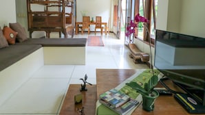Una sala de estar con sofá, mesa de centro, televisión y comedor con sillas y mesa.