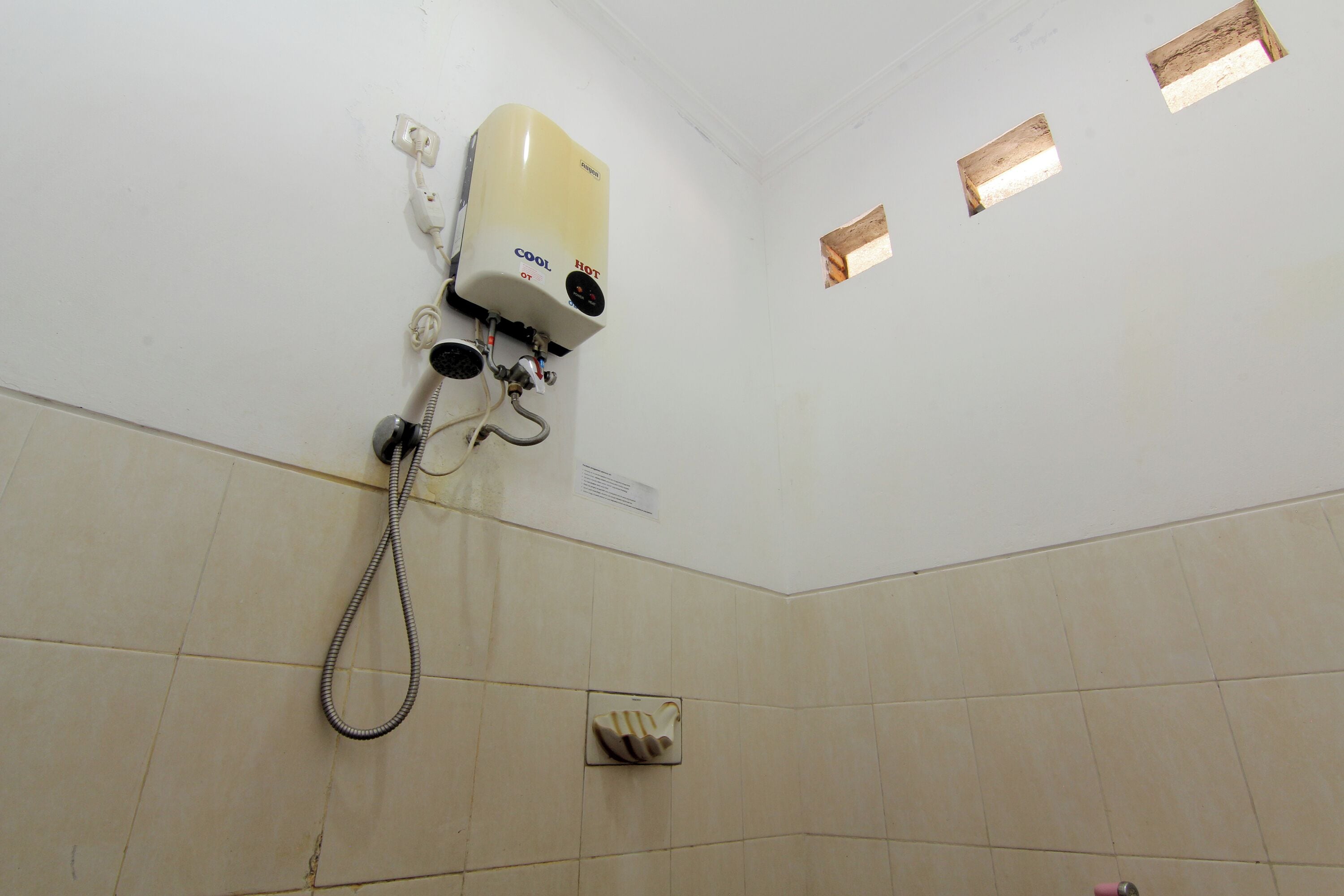 A bathroom with a wall-mounted heater, a shower hose, and a hand dryer.