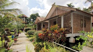 A brick building with a covered walkway and potted plants. - Disaster Oasis (Pakem)