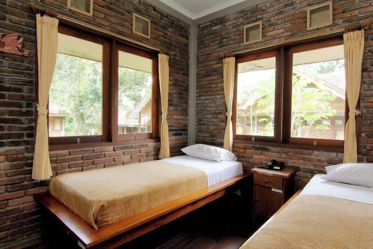 A room with two beds, wooden headboards, and brick walls.