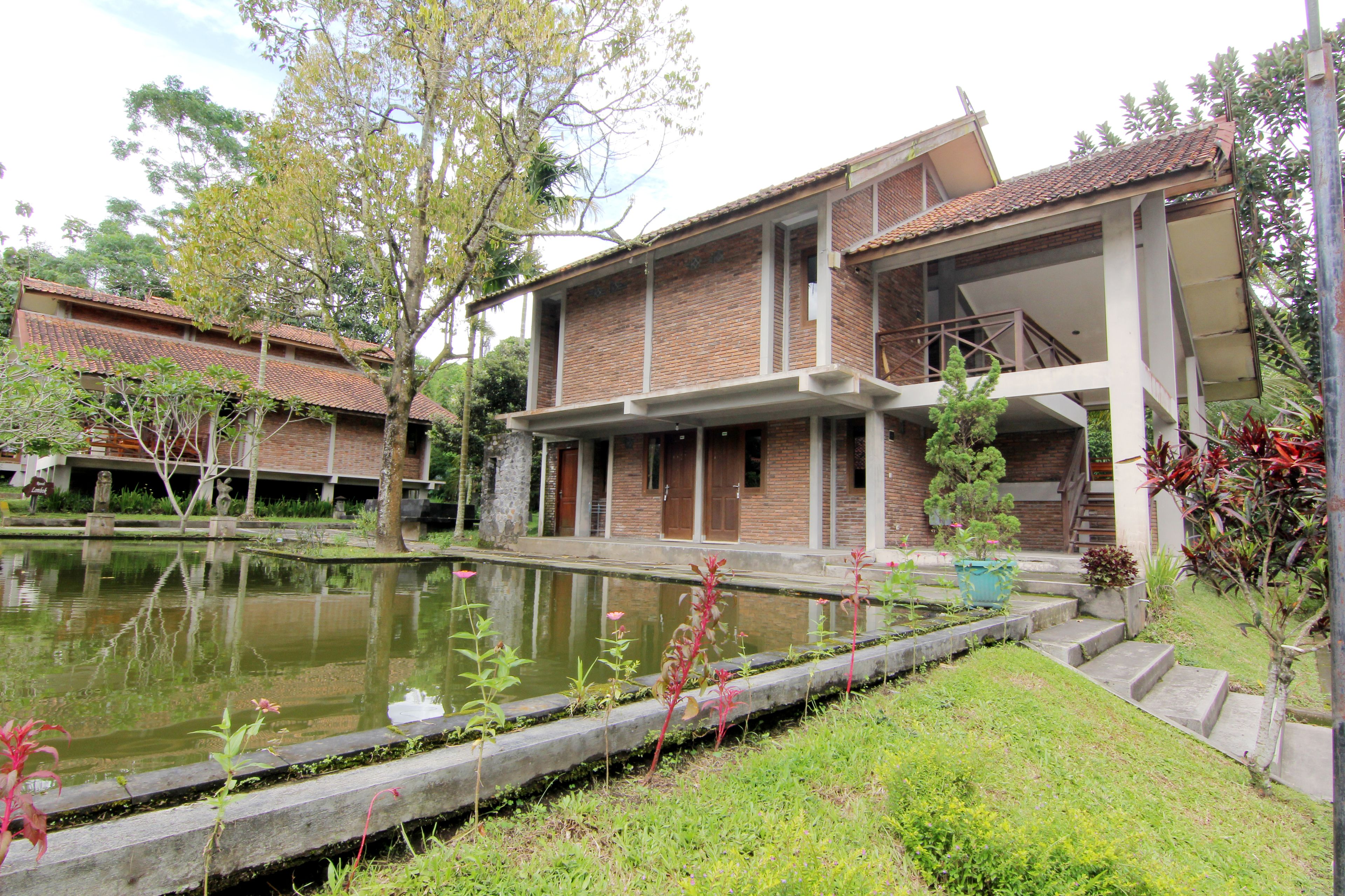 A building with a brick facade, a pond, and a staircase leading to a covered area.