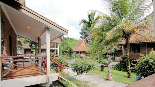 A courtyard with a bridge, palm trees, and a small water feature. - Disaster Oasis (Pakem)
