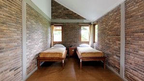 A room with two wooden beds, a brick wall, and a wooden floor. - Disaster Oasis (Pakem)