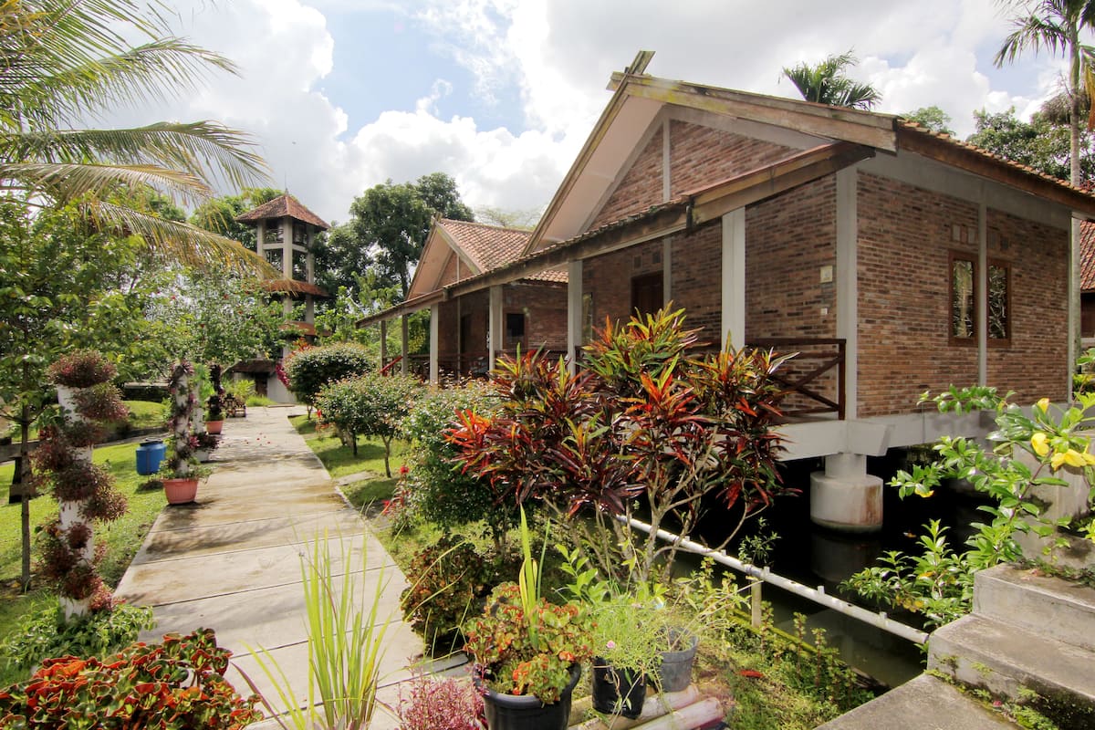 A brick building with a covered walkway and lush garden.