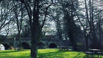 Un parc avec des tables de pique-nique et un pont en pierre.