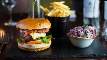 A burger with fries and coleslaw on a slate board.