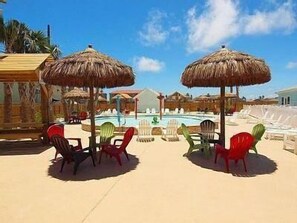 A poolside area with thatched umbrellas, lounge chairs, and a clear blue sky. - "Sea Anemone" Beautiful and Spacious, Great for Large Groups, Amazing Pool Area! (Corpus Christi)