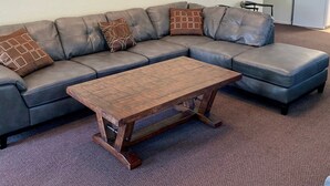 Una sala de estar con sofá modular, una mesa de centro de madera y arte abstracto en la pared.