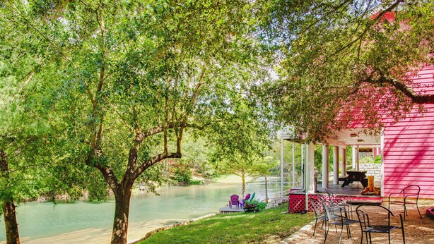 Un patio junto al río con mesas al aire libre y una zona cubierta.