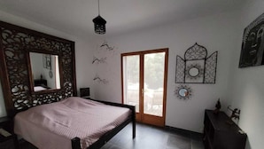 A bedroom with a bed, a dresser, a mirror, and a door leading to a balcony.