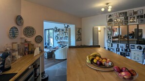 A spacious kitchen with a wooden countertop, a fruit bowl, and a bookshelf.