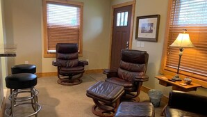 A room with two leather recliners, a wooden coffee table, and a bar stool. - Park Right by Your Door -1 BR, 1 Bath, Full Kitchen, 1st Floor Laundry. (Lansing)