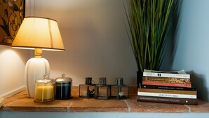 Eine Lampe, Kerzen und Bücher auf einem Regal.