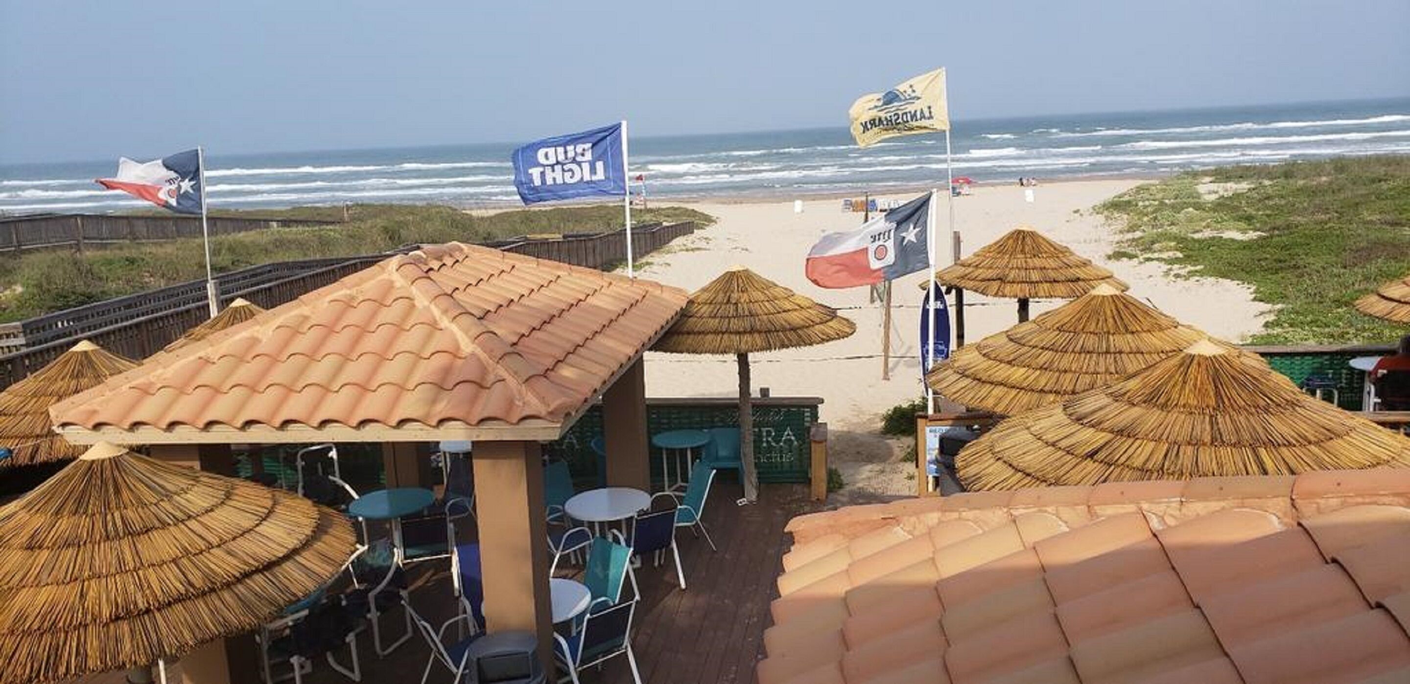 Een restaurant aan het strand met rieten parasols en terras.