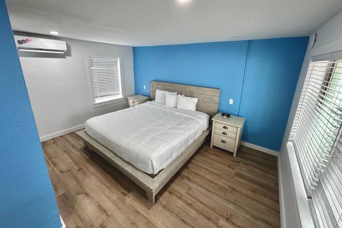 A bedroom with a bed, bedside tables, and a window with blinds.