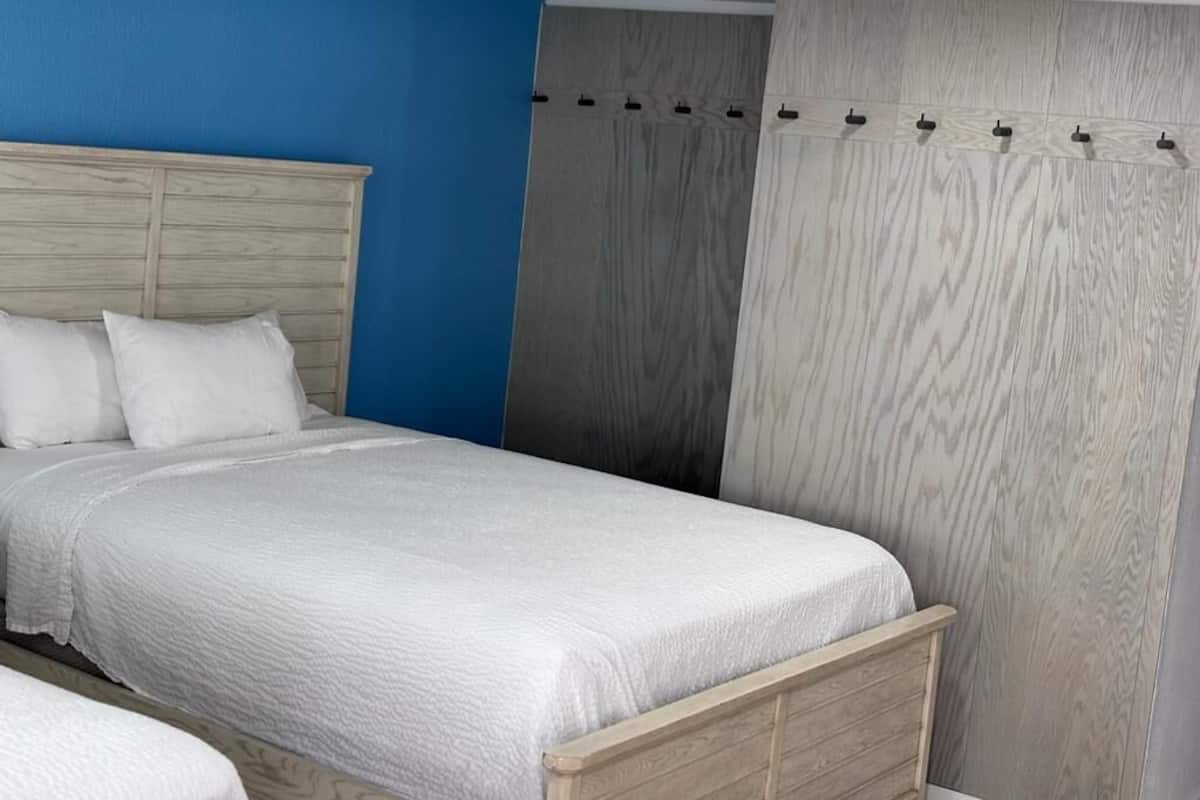 A bedroom with a bed, a blue wall, and a grey curtain.