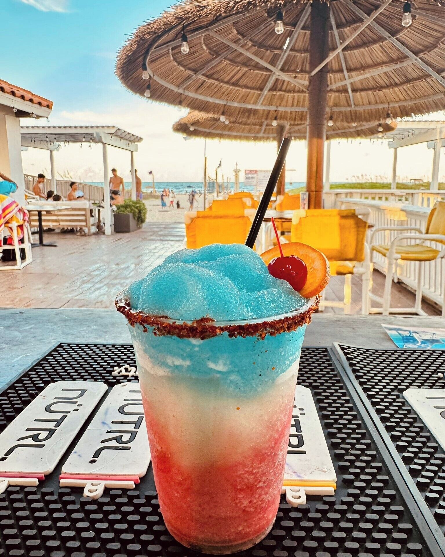 Een tropisch drankje op een tafel, met uitzicht op een strand op de achtergrond.