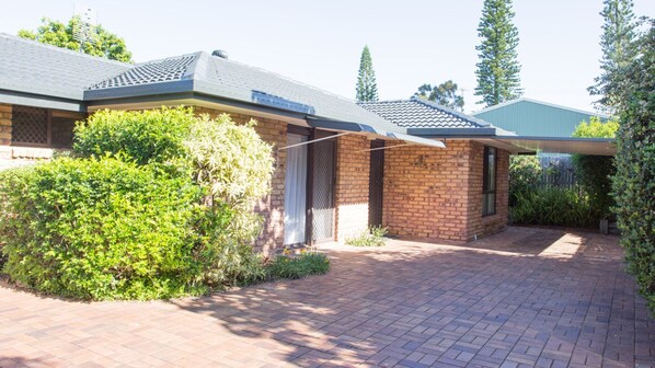 A residential property with a paved driveway, a brick house, and a covered outdoor area. - Wellington Parade 15a, Shelly Beach, Caloundra (SHELLY BEACH)