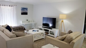 A living room with a TV, sofa, coffee table, and a lamp. - Wellington Parade 15a, Shelly Beach, Caloundra (SHELLY BEACH)