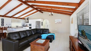A living room with a black leather sofa, a wooden coffee table, and a television on a wooden stand. - Michael Street 39, Golden Beach (GOLDEN BEACH)