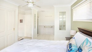 A bedroom with a bed, a nightstand, a lamp, a window with blinds, a ceiling fan, and a door. - Michael Street 39, Golden Beach (GOLDEN BEACH)