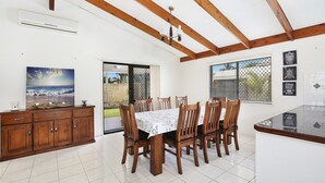 A dining area with wooden chairs and a table, a wooden cabinet, and a painting of a beach scene. - Michael Street 39, Golden Beach (GOLDEN BEACH)