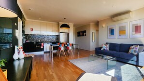 Een moderne woonkamer met een blauwe bank, een salontafel en een eethoek met stoelen en een tafel.