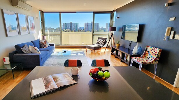 Een moderne woonkamer met een bank, salontafel en een eettafel met een schaal fruit.