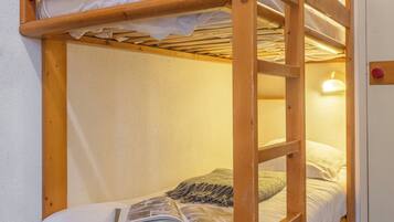 Un lit superposé avec une échelle, une porte avec une poignée rouge et un luminaire fixé au mur.