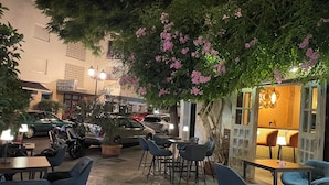 An outdoor cafe with tables and chairs, surrounded by greenery and parked cars. - Marbella apartment with swimming pool (Marbella)