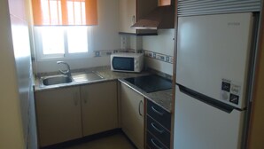 A compact kitchen with a sink, a microwave, a stove, and a refrigerator. - P. Maritimo 3º Pta 13 * LEK (Peñiscola)