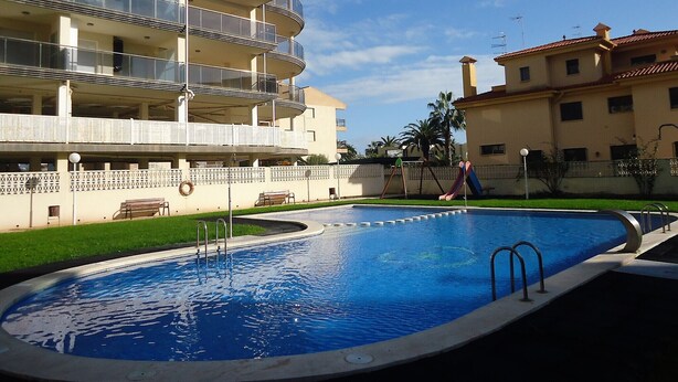 A swimming pool with a surrounding fence, a bench, and a playground with a slide. - P. Maritimo 3º Pta 13 * LEK (Peñiscola)