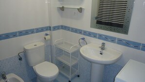 A bathroom with a toilet, bidet, sink, and a small shelf above the sink. - P. Maritimo 3º Pta 13 * LEK (Peñiscola)
