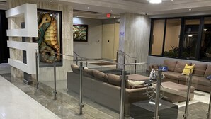 A modern lobby with a glass railing, a sofa, a coffee table, a large painting, and a ceiling light fixture. - Oceanfront Beachfront Penthouse, Isla Verde (Carolina)