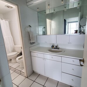 Une salle de bain avec des toilettes, un lavabo et un miroir.