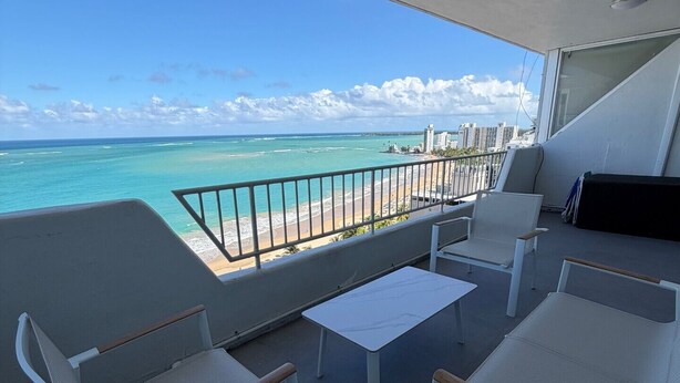 A balcony with white wicker chairs and a small table, overlooking a beach and ocean. - Oceanfront Beachfront Penthouse, Isla Verde (Carolina)