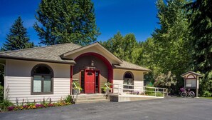 A small building with a red door and an 'Office' sign, surrounded by trees and a bicycle. - Mountain Harbor #202 2 Bedroom Condo (Whitefish)