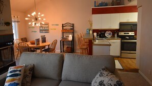 A compact living space with a dining area, kitchenette, and a sofa with patterned cushions. - Mountain Harbor #202 2 Bedroom Condo (Whitefish)