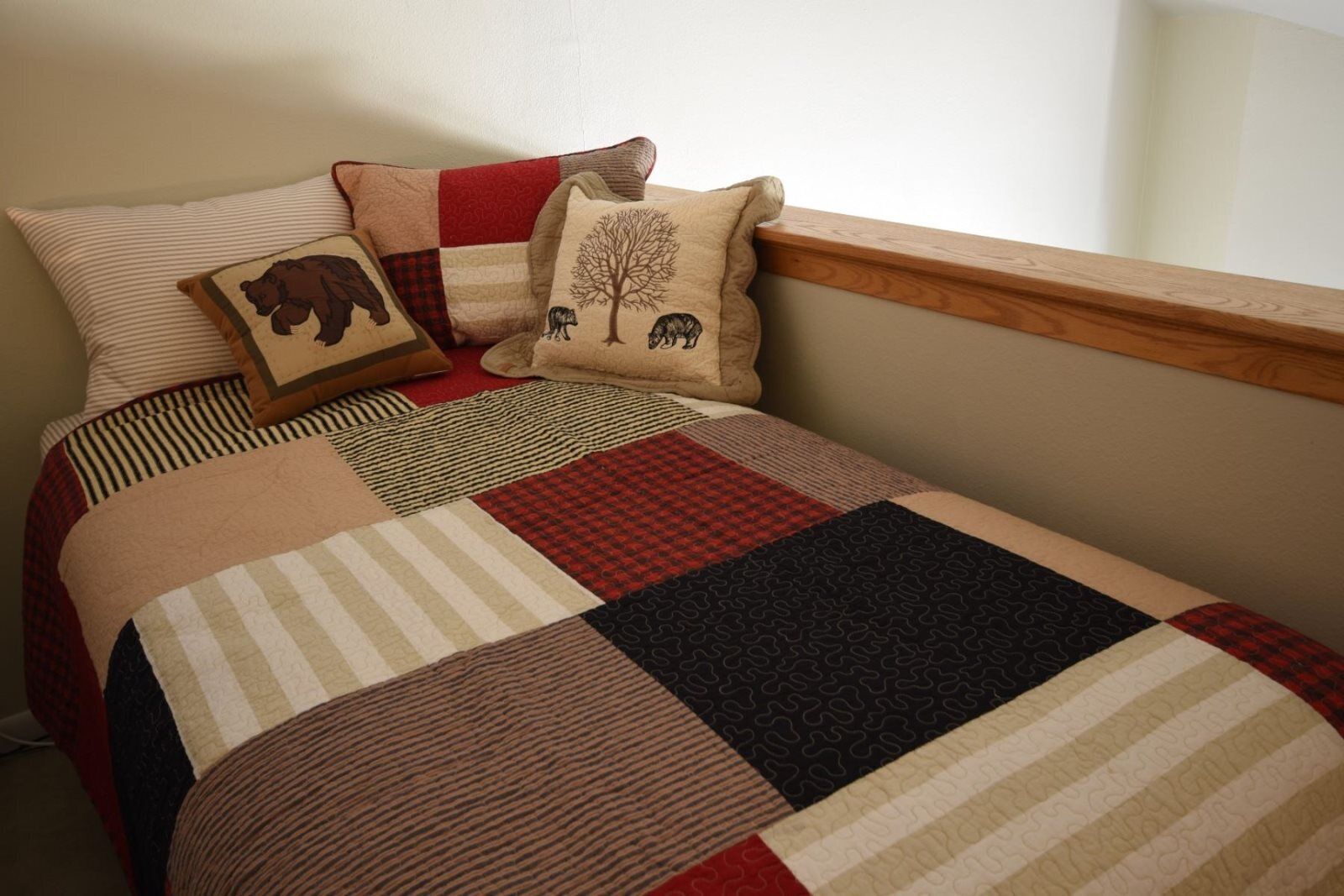 A bed with a patchwork quilt, striped pillows, and a wooden headboard.