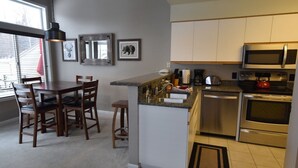 Een moderne keuken met een eetgedeelte, roestvrijstalen apparatuur en een groot raam.