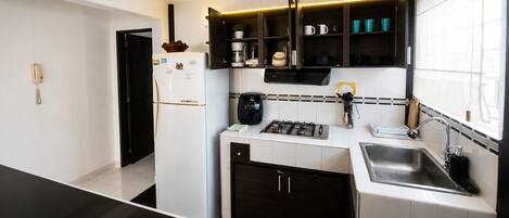 A modern kitchen with a built-in gas stove, a sink, and a coffee maker.