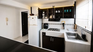 A modern kitchen with a built-in gas stove, a sink, and a coffee maker. - QuillaHost Thematic Apartment (Barranquilla)
