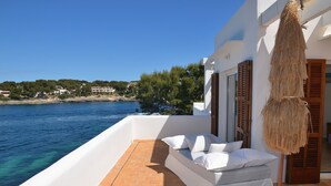 A white balcony with a white sofa and pillows, overlooking a clear blue sea and a coastal town. - House / Villa - Portocolom (Portocolom)