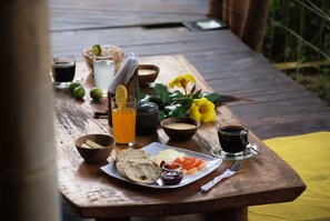 A wooden table with a breakfast spread including bread, eggs, and a plate of fruit, along with various drinks and condiments. - Kanta Sana (Dibulla)