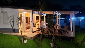 A modern house with an open-plan living area, a kitchen, and a dining space. - Bungalow F2 deluxe in beautiful Art Deco property and tropical garden (Petit Bourg)