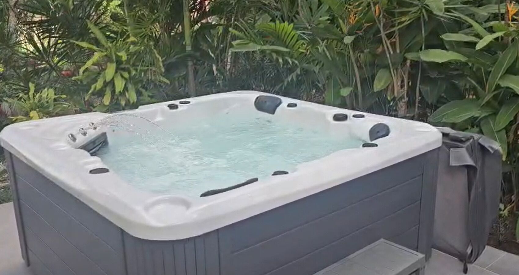 Uma banheira de hidromassagem com formato retangular, cercada por vegetação.