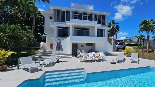 A modern two-story building with a pool area, outdoor seating, and palm trees. - Bungalow F2 deluxe in beautiful Art Deco property and tropical garden (Petit Bourg)